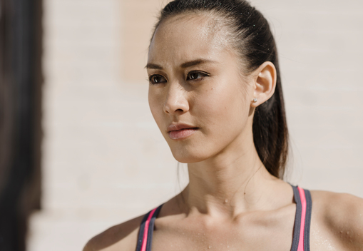 Head and shoulders photo of woman with black hair sweating after a workout