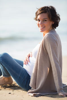 Smiling Pregnant Woman Sitting on Beach