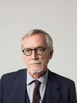 Headshot of an older man wearing glasses and a suit