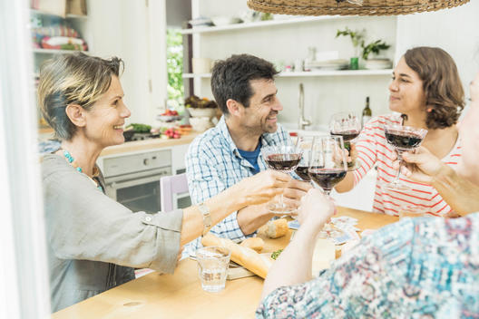 Adult friends making a toast with wine at dining table