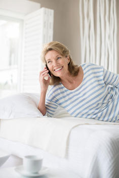Older woman talking on cell phone on bed