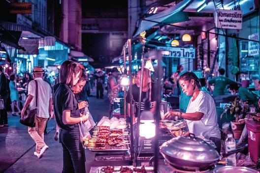 Bustling street with crowded business signs and open-late food vendor. Night scenes of the street of Bangkok at night.