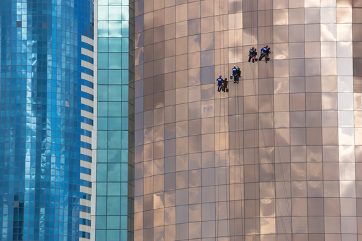 Maintenance workers hang from a skyscraper in the central business district of Astana, Kazakhstan.