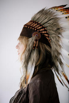 Profile of a blonde girl in an Indian head dress.