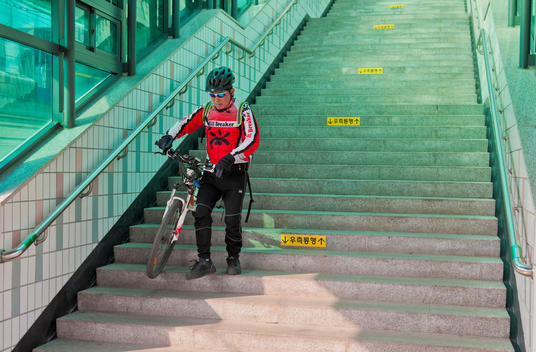 Cyclist Carries Bike Down Stairs
