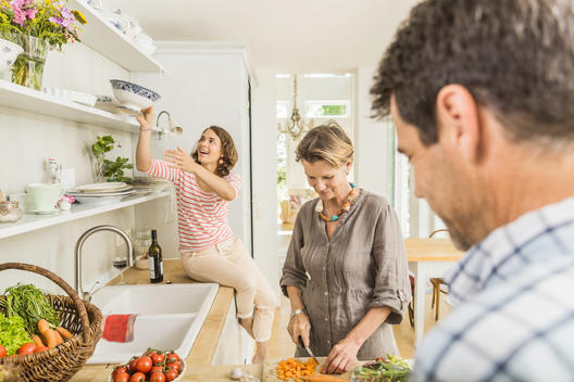 Three adults preparing fresh vegetables in kitchen