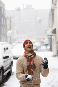 Man juggling snowballs in city