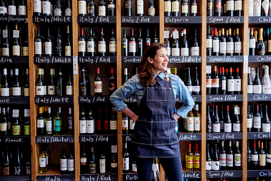 A small business owner stands happily in her wine store