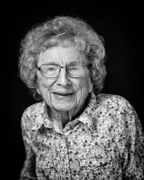 Black and white portrait of elderly woman wearing glasses with floral shirt smiling