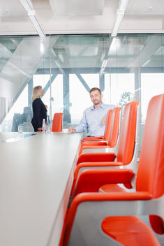 Man sitting on orange chair in conference room