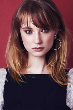 dark blonde model with fringe wearing a black top, silver earrings and silver eye makeup