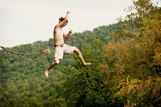 A Boy Swings Gracefully Into The Winooski River After Letting Go Of The Rope Swing.