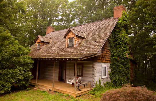 An old log cabin is nestled in the trees in the foothills of the Appalachian Mountains of North Carolina