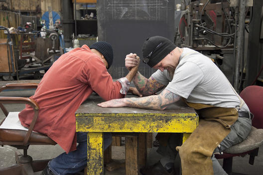 Workers arm wrestling in factory