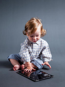 Nine month old baby boy playing with a tablet.