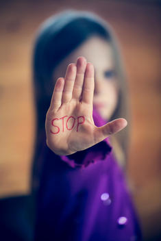 Little girl showing palm with the word STOP on it