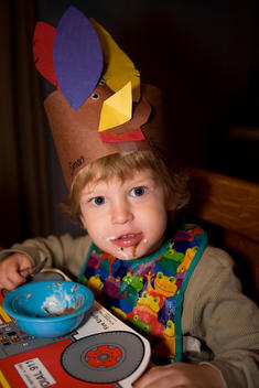 Young Boy Wearing A Thanksgiving Hat And Messily Eating Ice Cream