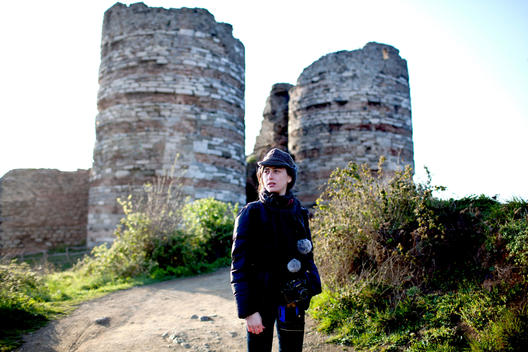Portraiture of a young Turkish woman front of an old ruined Genoese castle i