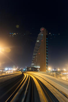 Dubai Metro rail tracks at night with skyline.