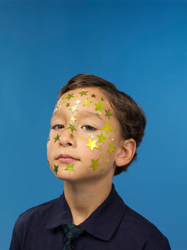 A boy has his face covered with gold star stickers