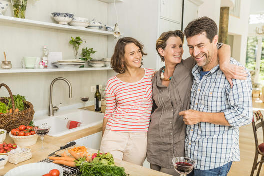 Portrait of three adults preparing fresh vegetables in kitchen