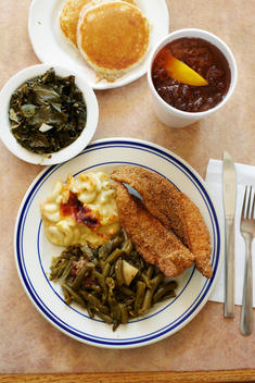 A Setting Of A Southern Meal Consisting Of Fried Catfish, Green Beans, Mac And Cheese, Corn Bread And Ice Tea.