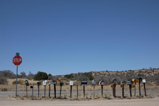row of letter boxes in sunny arid place with stop sign on the left