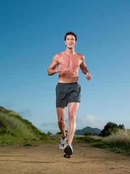 A muscular young man is running on a hiking trail