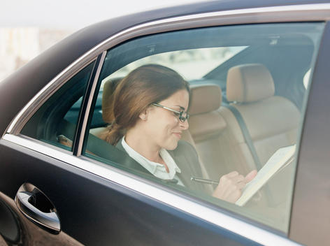 Businesswoman writing in backseat of car