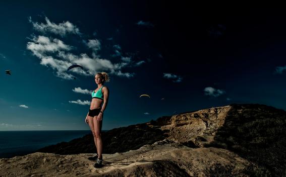 A girl in athletic wear rests on a trail in Torrey Pines over looking the Pacific Ocean in San Diego, CA.