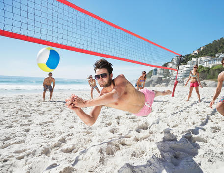 Man diving for volleyball on beach