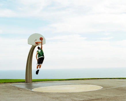Athlete Slam Dunking Basketball With Ocean View