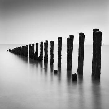 Wooden upright groynes or water breakers in the sea with long exposure