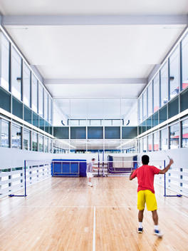 Two men playing badminton at Golden Lane Leisure Centre design renovation by Cartwright Pickard Architects, original design by Chamberlin Powell and Bon in 1952, Barbican, London, UK.