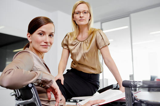 Businesswomen sitting in conference room, looking at camera