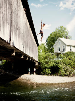 A Young Man Jumps Off Of The Covered Bridge In Waitsfield Into The Mad River.