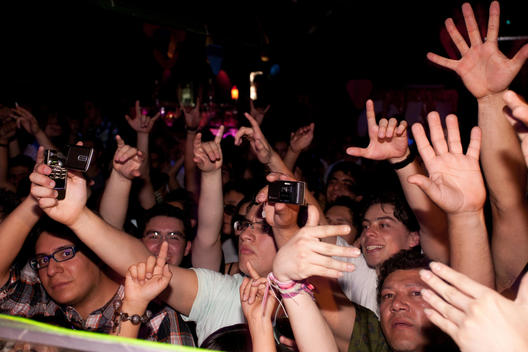 clubbers at DJ booth waving arms