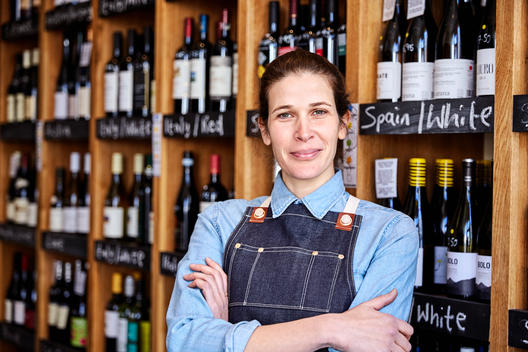 A small business owner stands for a portrait in her wine store