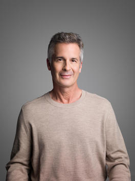 Handsome man in his 60's wears a grey sweater.