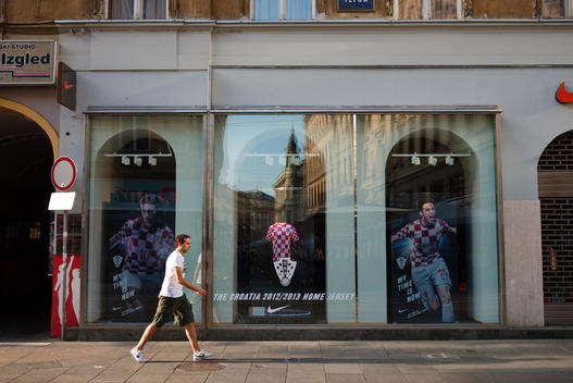 man on the sidewalk walking in front of a shop selling croatia national football team jerseys