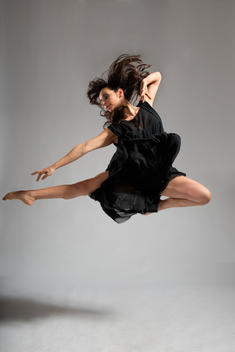 Female dancer in black dress is jumping