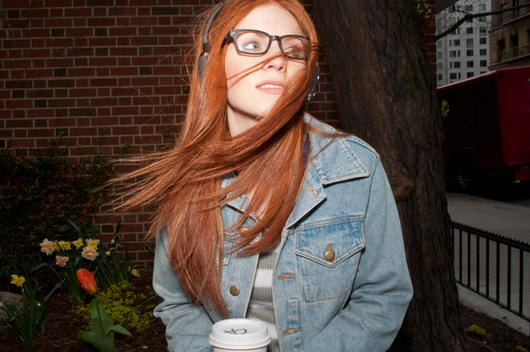 Young woman with takeaway coffee and hair across her face