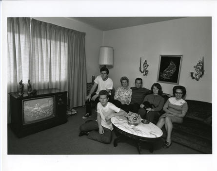 A family poses in their suburban home while watching football