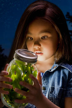 Chinese girl looking at fireflies in jar