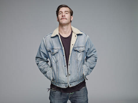 Portrait of man wearing jeans jacket in front of grey background