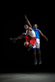 Male basketball players jumping and shooting ball