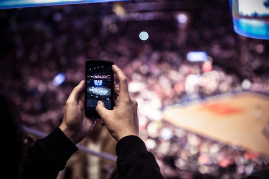 Man taking pictures of a basketball match with his phone