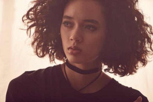 curly-haired model dressed casual/punk rock