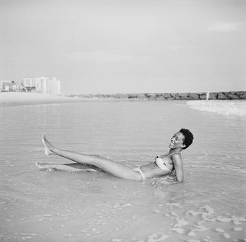 Fanta, a tall young African fashion model in bikini, is happy playing and laughing in ocean water at the empty beach in summer. Far Rockaway, Queens
