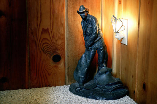 Cowboy statue by night light, with wood panel background.